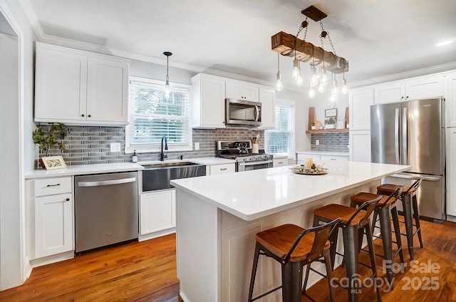 kitchen featuring stainless steel appliances, white cabinetry, a kitchen island, and hanging light fixtures