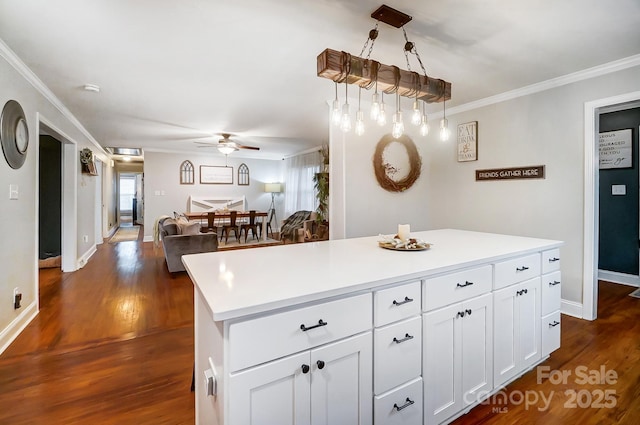 kitchen featuring decorative light fixtures, white cabinets, dark hardwood / wood-style flooring, a center island, and crown molding