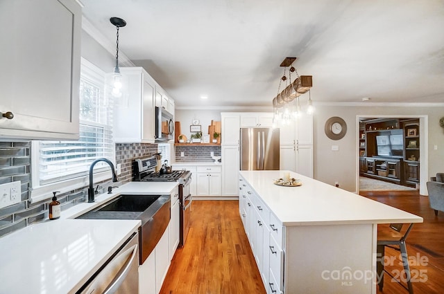 kitchen featuring stainless steel appliances, white cabinetry, a center island, and pendant lighting