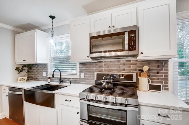 kitchen featuring appliances with stainless steel finishes, sink, hanging light fixtures, and white cabinets