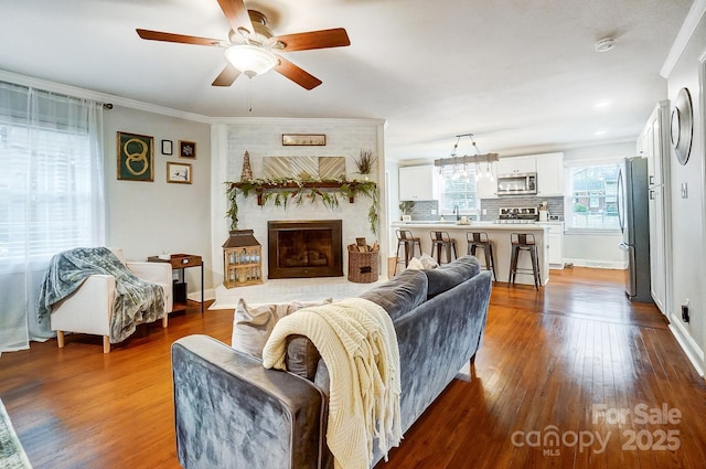 living room with ornamental molding, hardwood / wood-style floors, ceiling fan, and a fireplace