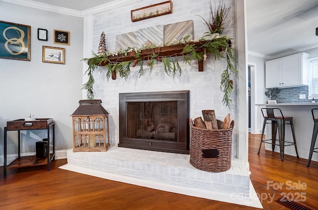 room details with ornamental molding, a fireplace, hardwood / wood-style floors, and backsplash