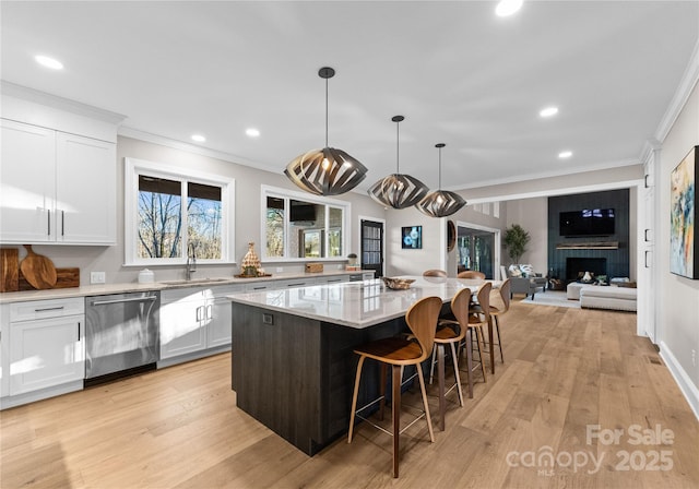 kitchen featuring stainless steel dishwasher, hanging light fixtures, sink, white cabinets, and a center island