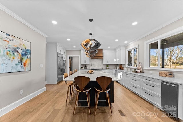 kitchen featuring white cabinetry, decorative light fixtures, a center island, and light stone counters