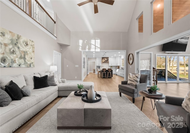 living room with high vaulted ceiling, light hardwood / wood-style flooring, and ceiling fan