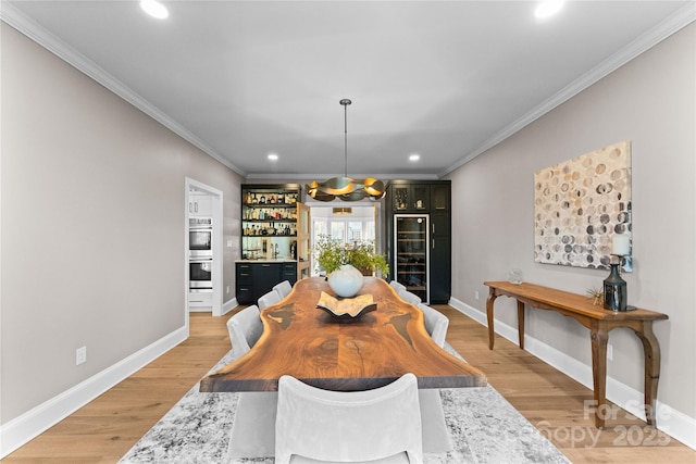 dining space with light hardwood / wood-style floors, beverage cooler, and crown molding