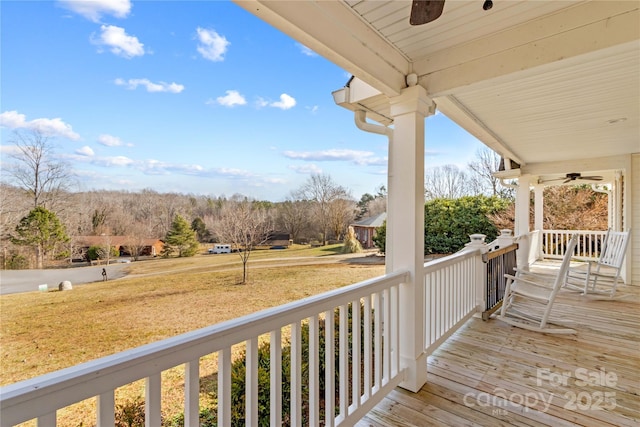 wooden deck featuring ceiling fan, a porch, and a lawn