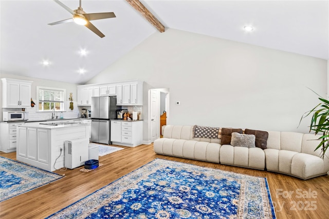 living room with ceiling fan, high vaulted ceiling, light wood-type flooring, and beam ceiling