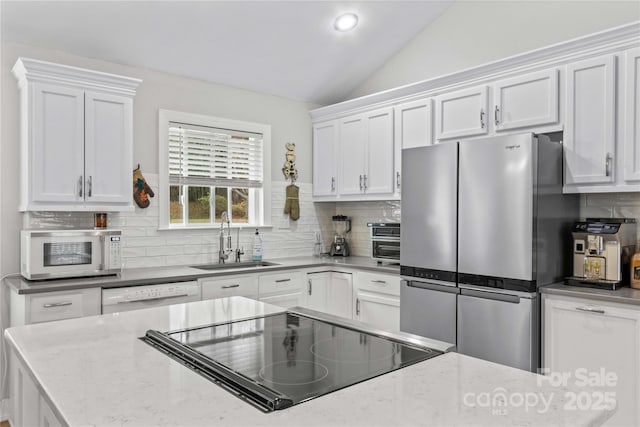 kitchen featuring sink, white appliances, tasteful backsplash, white cabinets, and vaulted ceiling