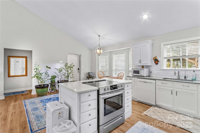 kitchen featuring sink, white appliances, a center island, white cabinets, and decorative light fixtures