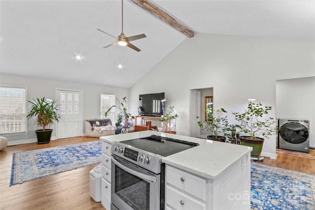 kitchen featuring washer / dryer, white cabinets, stainless steel range with electric cooktop, beam ceiling, and light hardwood / wood-style flooring