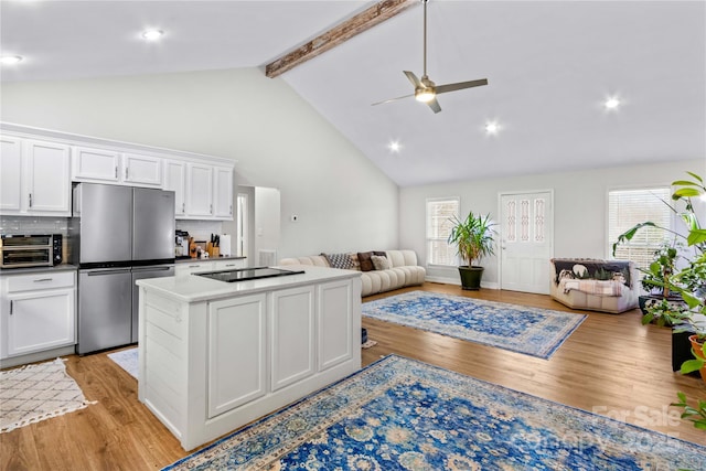 kitchen featuring stainless steel fridge, light hardwood / wood-style flooring, white cabinetry, beam ceiling, and a kitchen island