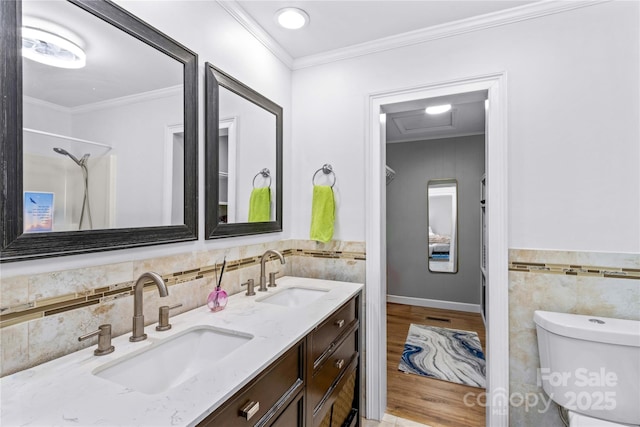 bathroom featuring wood-type flooring, tile walls, vanity, toilet, and crown molding