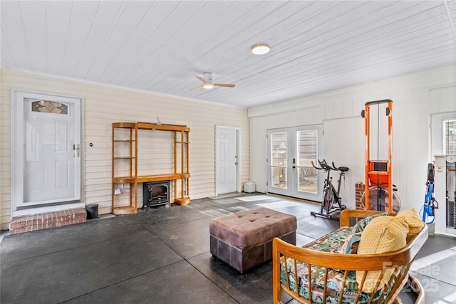 living room featuring french doors, ceiling fan, and a wood stove