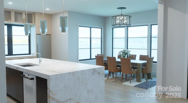 kitchen with sink, decorative light fixtures, a wealth of natural light, and an island with sink