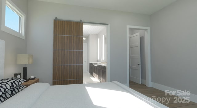 bedroom featuring ensuite bathroom, a barn door, and hardwood / wood-style floors