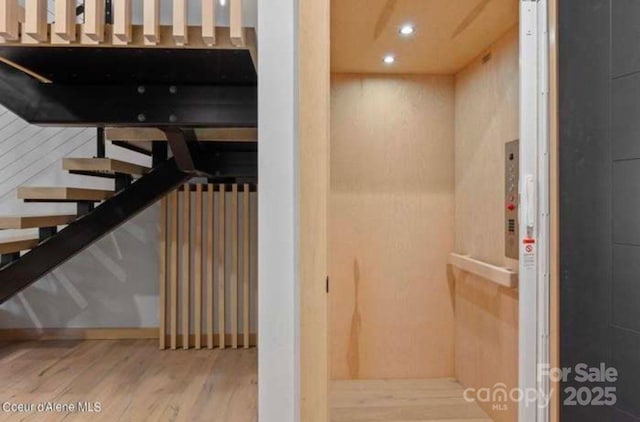 stairway with hardwood / wood-style flooring and elevator