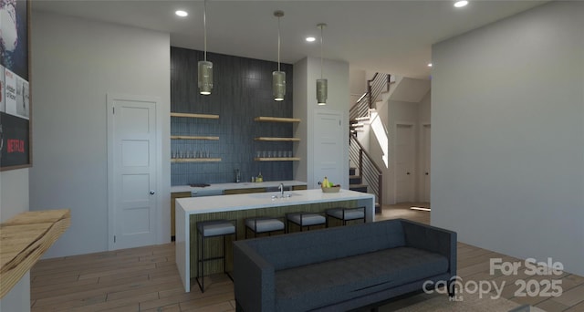 interior space featuring hanging light fixtures, hardwood / wood-style flooring, and an island with sink