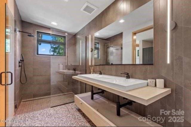 bathroom featuring double sink, tile patterned floors, and walk in shower