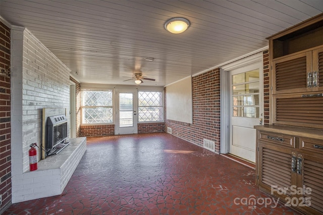 unfurnished living room with brick wall, heating unit, wood ceiling, and ceiling fan