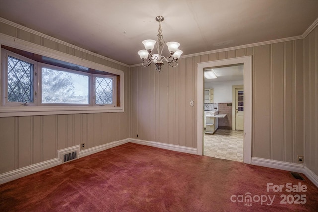 spare room featuring a notable chandelier, crown molding, and carpet flooring