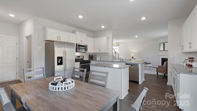 kitchen featuring light stone counters, a center island, white cabinetry, and appliances with stainless steel finishes