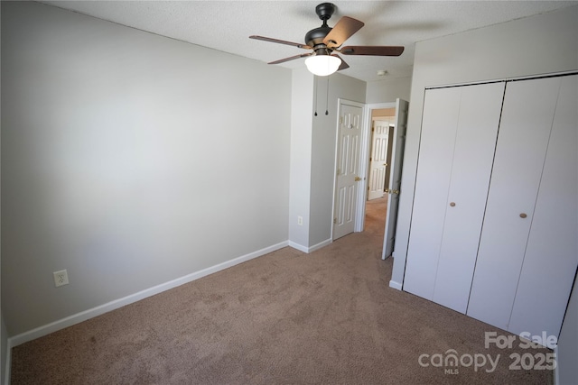 unfurnished bedroom featuring ceiling fan, light colored carpet, a closet, and a textured ceiling