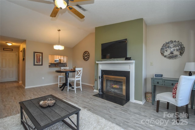 living room with hardwood / wood-style flooring, ceiling fan, and vaulted ceiling