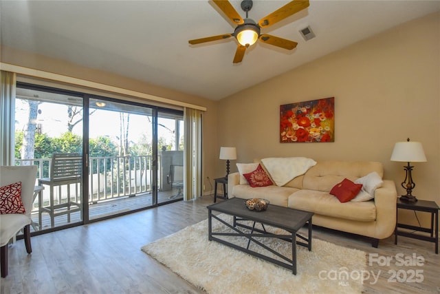 living room featuring ceiling fan, hardwood / wood-style floors, and vaulted ceiling