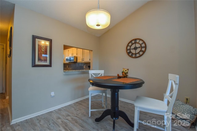 dining room featuring light hardwood / wood-style floors and lofted ceiling