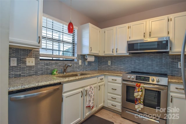 kitchen featuring sink, white cabinets, decorative backsplash, and appliances with stainless steel finishes