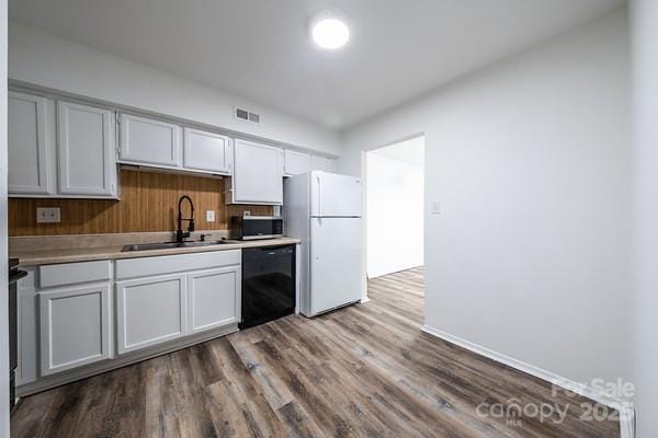 kitchen featuring sink, wood-type flooring, black dishwasher, and white refrigerator