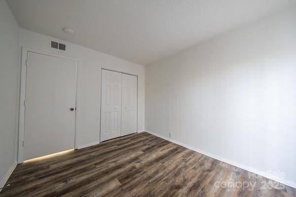 unfurnished bedroom with a closet and dark hardwood / wood-style floors