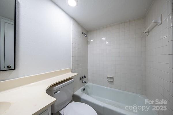 full bathroom featuring tiled shower / bath, vanity, and toilet