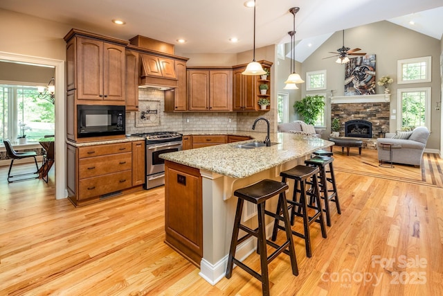 kitchen featuring gas range, a kitchen breakfast bar, sink, black microwave, and kitchen peninsula