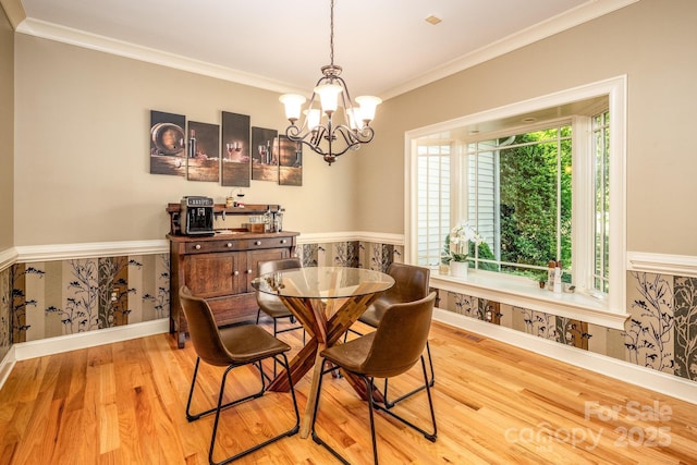 dining area with light hardwood / wood-style flooring, crown molding, and a notable chandelier