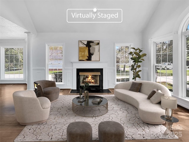 living room with decorative columns, hardwood / wood-style floors, and vaulted ceiling