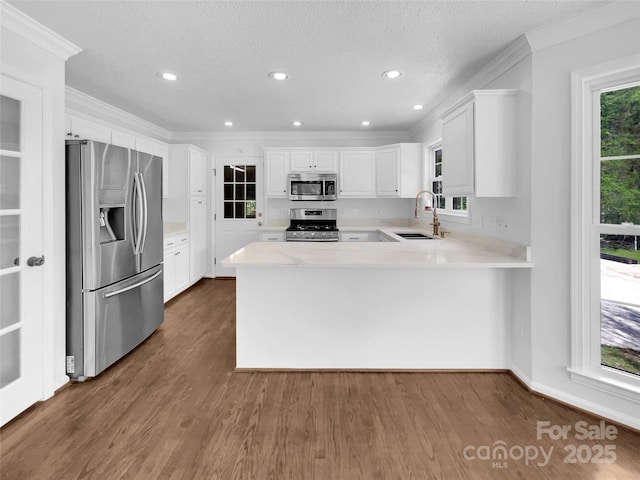 kitchen with white cabinetry, sink, kitchen peninsula, dark wood-type flooring, and stainless steel appliances