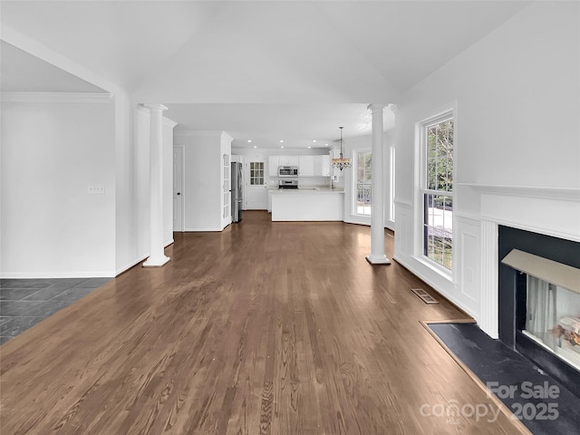 unfurnished living room with dark hardwood / wood-style flooring, a multi sided fireplace, ornamental molding, a chandelier, and decorative columns