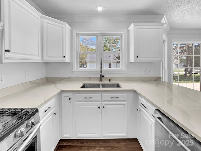 kitchen featuring a textured ceiling, white cabinetry, stainless steel dishwasher, sink, and light stone counters