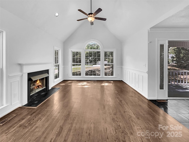 unfurnished living room featuring ceiling fan, dark wood-type flooring, ornamental molding, and vaulted ceiling