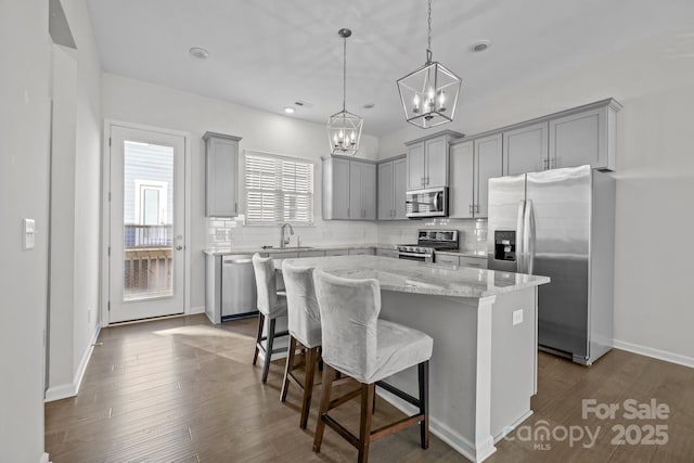 kitchen featuring a kitchen island, sink, a kitchen breakfast bar, hanging light fixtures, and stainless steel appliances