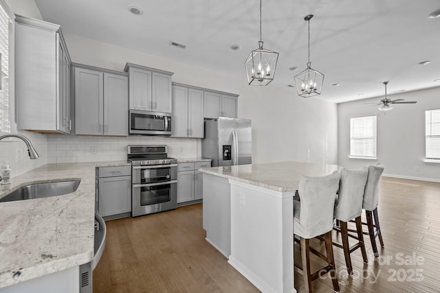 kitchen featuring sink, decorative backsplash, hanging light fixtures, a center island, and stainless steel appliances