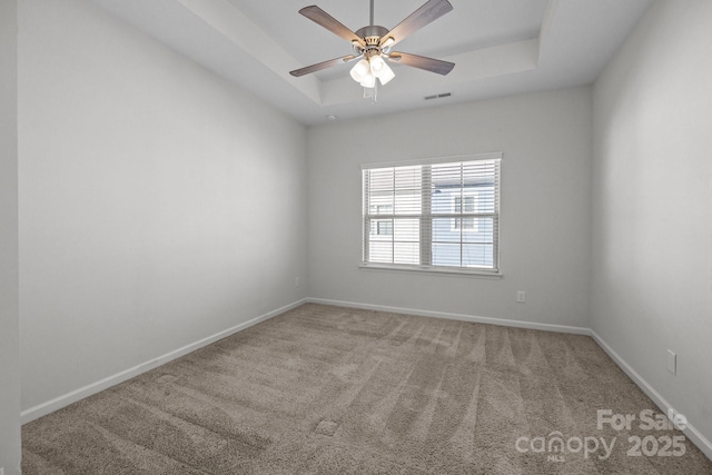 unfurnished room featuring a raised ceiling, carpet floors, and ceiling fan