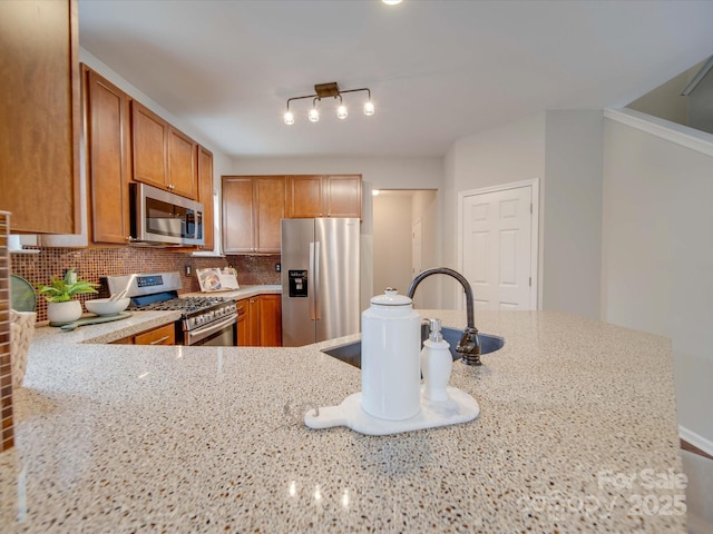 kitchen featuring kitchen peninsula, tasteful backsplash, light stone countertops, and appliances with stainless steel finishes