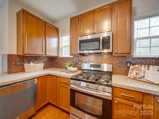 kitchen featuring light stone counters, decorative backsplash, and stainless steel appliances