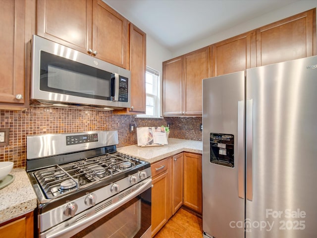 kitchen with light stone countertops, backsplash, and appliances with stainless steel finishes