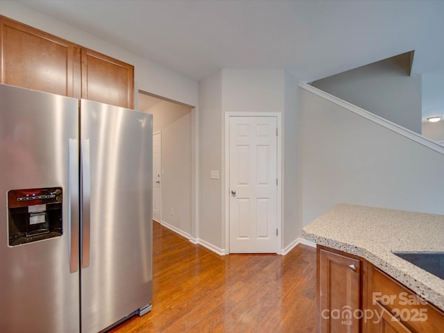 kitchen featuring light stone counters, light hardwood / wood-style flooring, and stainless steel refrigerator with ice dispenser