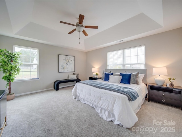 bedroom featuring ceiling fan, multiple windows, and a raised ceiling