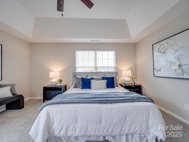 carpeted bedroom featuring ceiling fan and a tray ceiling